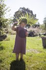 Дівчина стоїть в саду тримає лист папороті — стокове фото