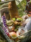 Корзина из проволоки с продуктами питания и столовыми приборами на траве — стоковое фото