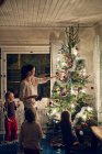 Madre con hijas decorando árbol de Navidad - foto de stock