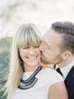 Groom kissing bride cheek, focus on foreground — Stock Photo