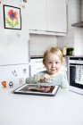 Menino usando tablet digital na cozinha, foco seletivo — Fotografia de Stock