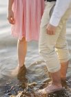 Couple standing barefoot in water, selective focus — Stock Photo