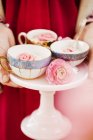 Frau hält Kuchen mit Tassen mit Marzipan-Rosen — Stockfoto