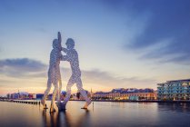 Molekülmännchen-Skulptur an Spree und beleuchtetem Flussufer in der Abenddämmerung — Stockfoto