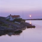 Житловий будинок і човен на березі моря на заході сонця — стокове фото