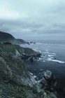 Scenic view of coastline under cloudy sky at dusk — Stock Photo