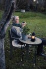 Зріла жінка розслабляється з чашкою кави на задньому дворі — стокове фото
