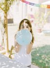 Cute girl inflating blue balloon — Stock Photo