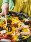 Frau kocht Paella mit Meeresfrüchten auf Grill — Stockfoto