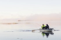 Young men fishing in lake at sunset — Stock Photo