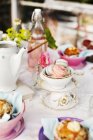 Served table with macarons in cup and teapot — Stock Photo