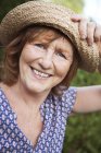 Portrait of smiling senior woman wearing straw hat — Stock Photo