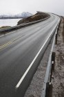 Sinuoso camino costero con vistas a las montañas nevadas - foto de stock