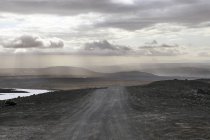 Blick auf Schotterpiste unter bewölktem Himmel, Island — Stockfoto