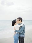 Couple embracing and kissing on beach, focus on foreground — Stock Photo