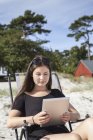 Adolescente usando tablet digital na praia — Fotografia de Stock