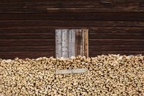 Pile of firewood beside wooden shed — Stock Photo