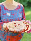 Женщина держит поднос с чизкейком, украшенный ягодами — стоковое фото