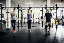 Les jeunes femmes et l'homme sauter corde à la salle de gym — Photo de stock