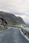 View of road in mountainous landscape under cloudy sky — Stock Photo