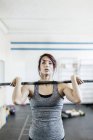 Young woman training with barbell in gym — Stock Photo