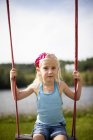 Menina com cabelo loiro sentado no balanço da corda — Fotografia de Stock