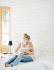 Metà della donna adulta che tiene il bambino in braccio in camera da letto — Foto stock