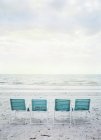 Quatre chaises pliantes vides sur la plage — Photo de stock