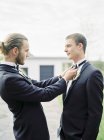 Noivo ajustando parceiro laço gravata no casamento gay — Fotografia de Stock