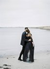 Giovane coppia formalmente vestita a piedi lungo la spiaggia — Foto stock