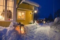 Veduta di case illuminate con sentiero sulla neve — Foto stock