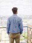 Rear view of man looking at view from balcony — Stock Photo