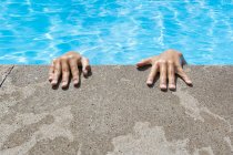 Wet hands on edge of swimming pool — Stock Photo