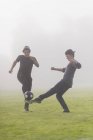 Ragazzi adolescenti che giocano a calcio a prato nebbioso — Foto stock