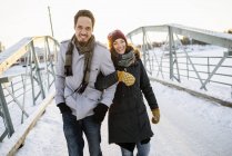 Молодая пара, идущая по пешеходному мосту зимой, сосредоточьтесь на переднем плане — стоковое фото