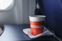 Disposable cup on airplane table, close up shot — Stock Photo