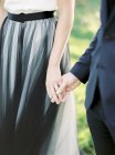 Cropped view of bride and groom holding hands — Stock Photo