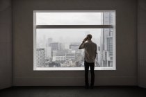 Mann telefoniert und schaut durch Fenster — Stockfoto