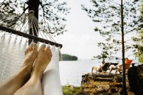 Jovem relaxante na rede por lago — Fotografia de Stock