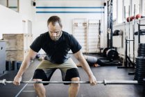 Junger bärtiger Mann beim Gewichtheben in Turnhalle — Stockfoto