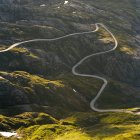 Estrada sinuosa que se estende através do vale verde da montanha — Fotografia de Stock