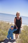 Mother and son walking along beach footpath — Stock Photo