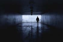 Женщина ночью в тёмном туннеле, избирательный фокус — стоковое фото