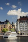 Fähre in der Nähe von Altstadtgebäuden im hellen Sonnenlicht, Stockholm — Stockfoto
