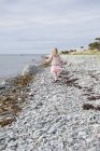 Vue arrière de la fille marchant par la mer — Photo de stock