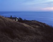 Single house on hill with sea on background at dusk — Stock Photo