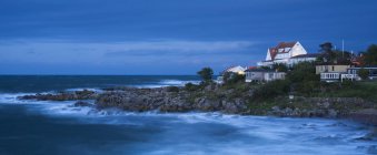 Maisons sur le littoral avec vagues de surf au crépuscule — Photo de stock