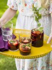 Woman holding yellow tray with carafe and glasses of sangria — Stock Photo