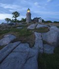 Hammeren Lighthouse on rocky hill illuminated at dusk — Stock Photo