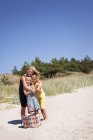 Madre abrazando a dos hijas en la playa — Stock Photo